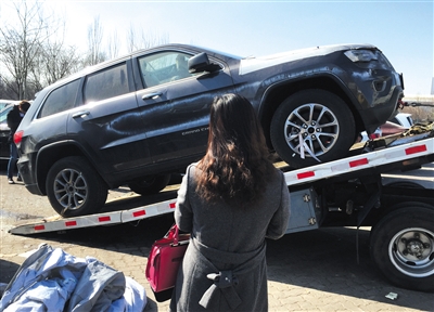 2月25日，天津中电物流停车场，一女子花30余万元购买的一辆大切诺基，准备用拖车拖走。经记者查询，此停车场有23辆Jeep车为天津港爆炸受损车辆。