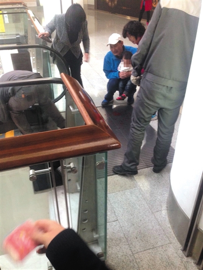 女童手指被夹断后，蹲在地上的爷爷把她抱在怀里。目击者供图