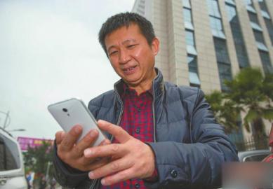 30日，陈满在海南省高级人民法院大门外用手机给家人发信息。