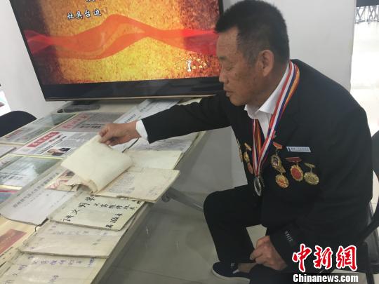 图为谷殿明老人翻看为市民维修灶具的登记信息。 李洋 摄