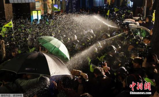 资料图：当地时间2015年4月16日，韩国首尔，“岁月号”沉没事件的遇难者家属和支持民众在首尔广场举行追思会，会后情绪激动人群开始游行，并与警方发生激烈冲突。图为警方向示威者喷射含有辣椒水的液体，以驱散人群。