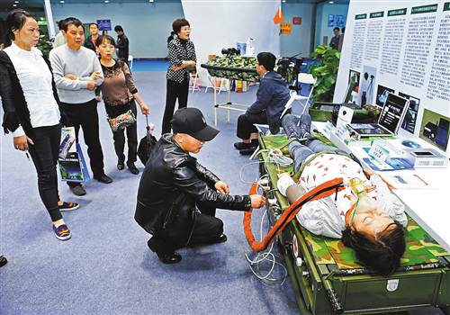 4月22日，南坪国际会展中心，第十二届重庆高交会暨第八届国际军博会上，市民正在军队科技展团体验直升机搭载急救单元。

　　记者 谢智强 摄