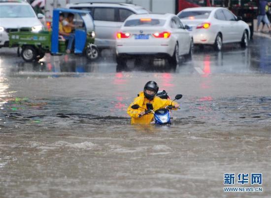 6月1日，市民在江西九江经济技术开发区积水路段推着摩托车涉水前行。当日，江西九江遭受暴雨袭击，九江市城区部分路段积水严重，交通受阻。江西九江市气象台于6月1日14时30分发布暴雨蓝色预警信号。新华社发（胡国林 摄）