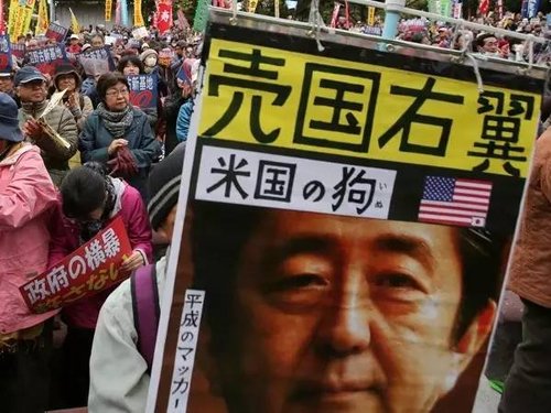 2015年11月，抗议者举着反对安倍的宣传画，抗议美军在冲绳修建新基地。
