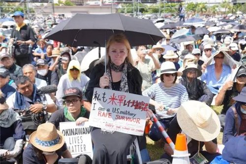 19日，冲绳县首府那霸市，一名抗议者手举“我是美军暴行受害者”的标语。