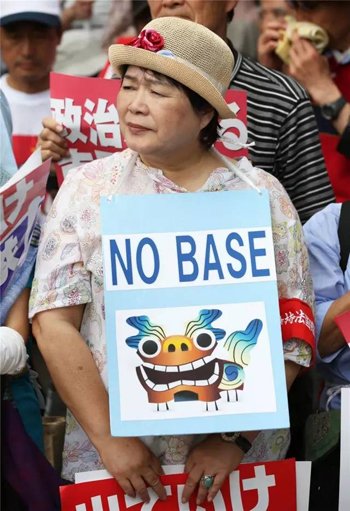 6月19日，在日本首都东京，一名市民胸前挂着“不要(美军)基地”的标语。