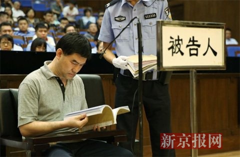 犯罪嫌疑人在察看法庭出示的银行转账信息的证据。新京报记者 尹亚飞 摄