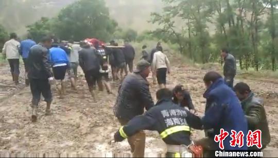 图为消防救援人员和村民艰难行走在泥石流区域 钟欣 摄