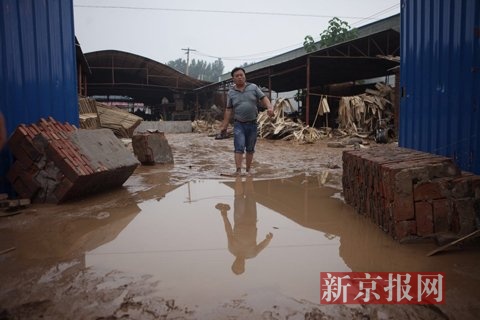 7月23日，桥东板厂门口，梓阳爸爸张苏辉从灾后工厂里走出来。新京报记者 王嘉宁 摄