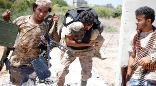 2016年7月31日，利比亚团结政府部队在苏尔特与伊斯兰国武装分子作战。政府军的一名战士掩护另外一名战士背着伤员撤离。（图片来源：路透社）