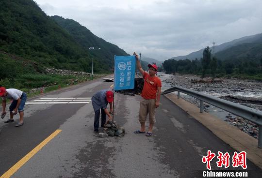 洪水中，漂流公司职工徒步在危险路段设置警示标志30余处，公司彩旗成为一道独特的风景线。 天野 摄