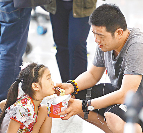 一位在机场滞留的家长喂女儿吃面。 刘国权摄