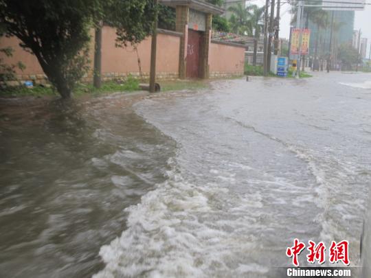 图为17日下午，海南省临高县的县城，部分路段积水成河，车在水中行驶如行舟。 付美斌 摄