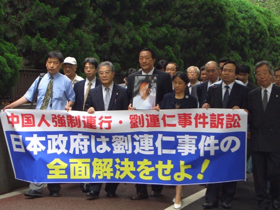 2005年6月23日，刘连仁事件诉讼团、律师团和声援团手执声援横幅正在步入东京高等法院大门。当日东京高等法院作出否定刘连仁一审胜诉的判决。队伍前列左起管建强（左一）、森田太三律师（左二）、高桥融律师（左三）、原告刘焕新（刘连仁之子，左四）、康健（中国律师，左五）、傅强（中国律师，左六）、小野寺利孝律师（左七）。资料图片
