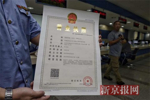 商人员展示新的营业执照。 新京报记者 王嘉宁摄