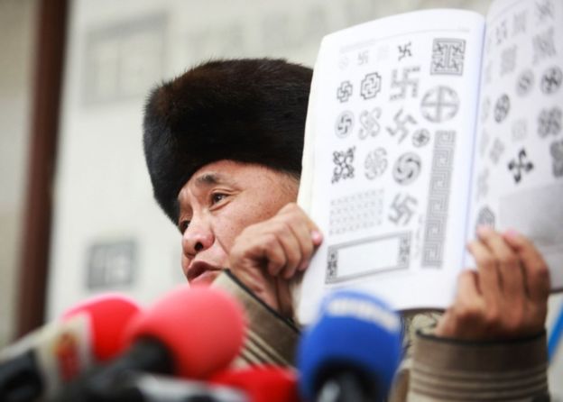 苏赫巴特尔的父亲展示了一本带有传统“卐”图形的书，介绍这一符号在蒙古的历史。