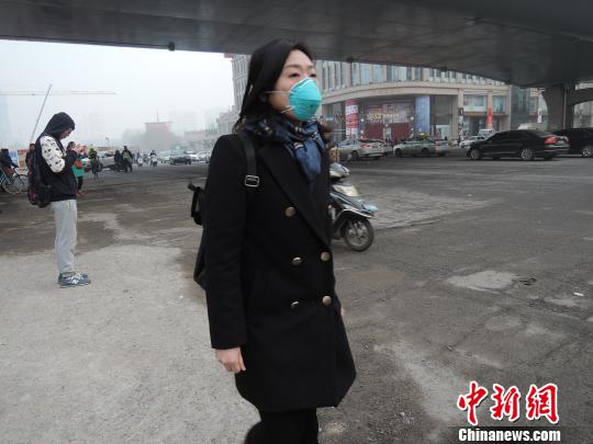 一位路人戴着防雾霾口罩匆匆而过。 韩章云 摄