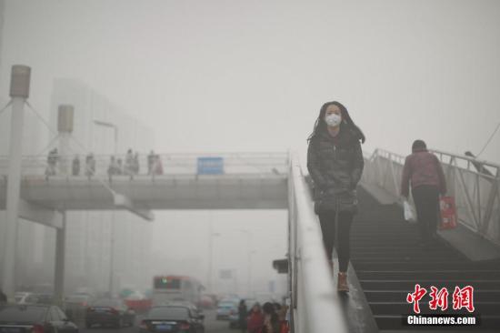 资料图 戴着口罩的行人从天桥上走过。中新社记者 佟郁 摄