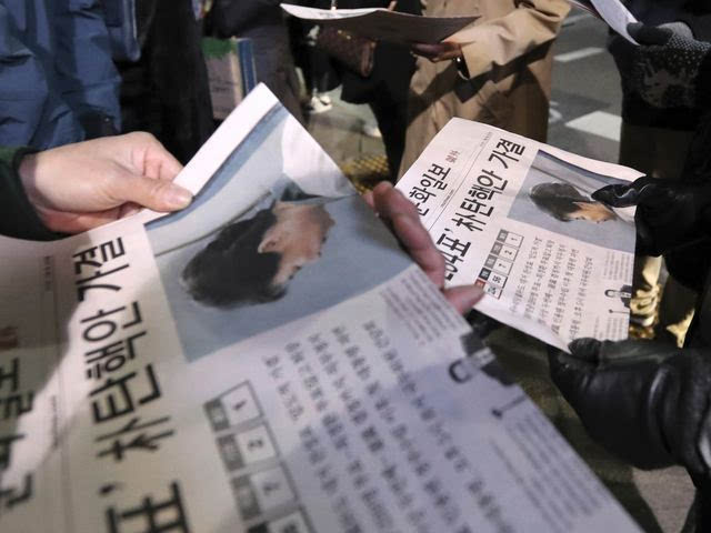 首尔，一名商贩向行人分发刊有朴槿惠弹劾案新闻的报纸。（新华/美联）
