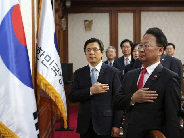 韩国总理黄教安（左）在内阁会议上向国旗致敬。（新华/美联）