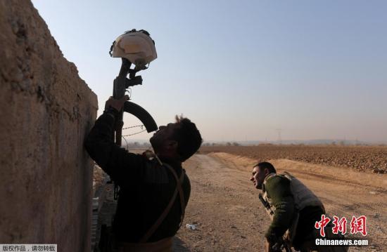  资料图：在摩苏尔东南部的Al-Qasar，一名伊拉克士兵用头盔作为诱靶，来确定极端组织人员的位置。