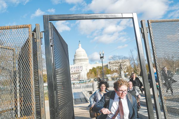 特朗普的就职典礼20日将在华盛顿举行。图为几名行人18日正穿过国会山前的安保围栏。