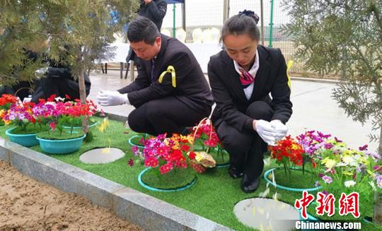 图为:安放骨灰坛后,礼仪师向骨灰坛撒花、盖土。 刘小红 摄