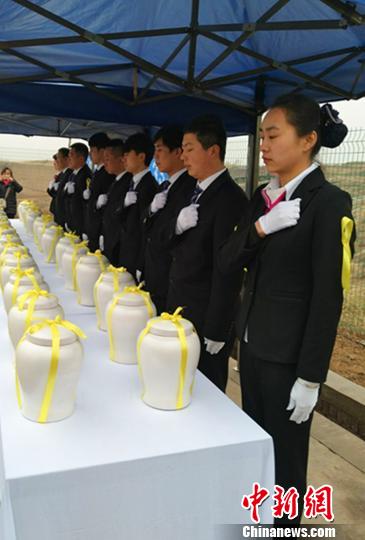 图为:礼仪师为亡灵系上“守护节”后,面朝30具骨灰行礼。 刘小红 摄