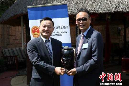 全非洲中国和平统一促进会会长李新铸(右)代表南非华人社区向杨培栋副总领事赠送纪念品。 宋方灿 摄