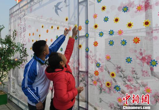 市民在寄语百花墙上贴上花朵表达思念。 张瑶 摄