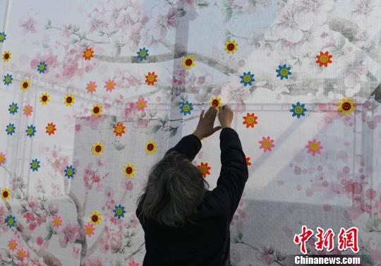 市民在寄语百花墙上贴上花朵表达思念。 张瑶 摄