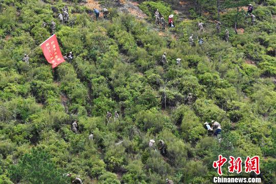长汀县由于长期受水土流失影响,山地上虽有植被,但均生长不良,20多年的林木难以成材,林下草灌退化,土壤表土流失,仅剩心土,形成了“远看青山在,近看水土流”的景象。图为官兵与百姓一起种植树苗。 赖桥泉 摄