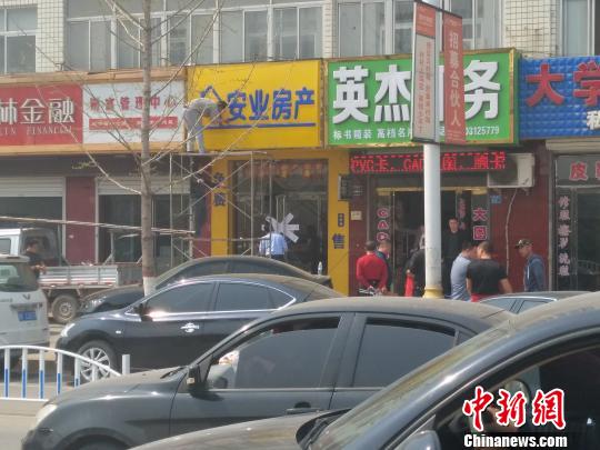 一名房产中介员工在被封的门店上修缮招牌　王天译　摄