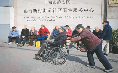 在上海，市民施爱玲推着丈夫章学军前往社区卫生服务中心。2013年，上海市静安区彭浦新村街道推出面向失能失智老人的民生服务项目“惠智驿站”，由政府出资购买社会服务，导入医护志愿者和社区志愿者等多方力量，解决失能失智老人的居家养老问题。新华社记者 裴 鑫摄