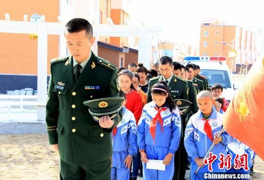 图为边防官兵和小学生为革命先烈默哀。 张辉 摄