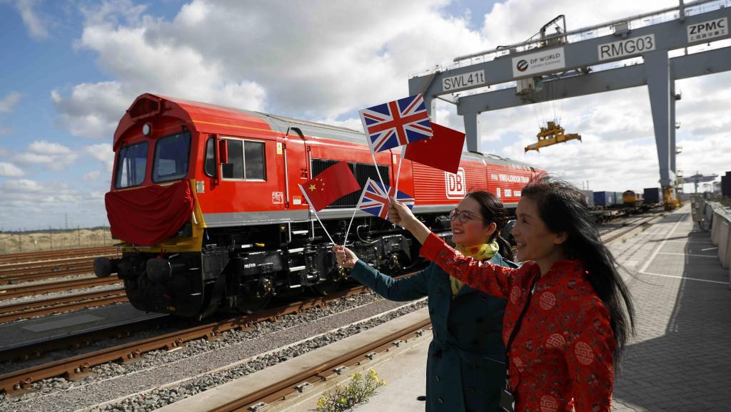 中国女子为首列英国开往中国的货车启动挥舞旗子