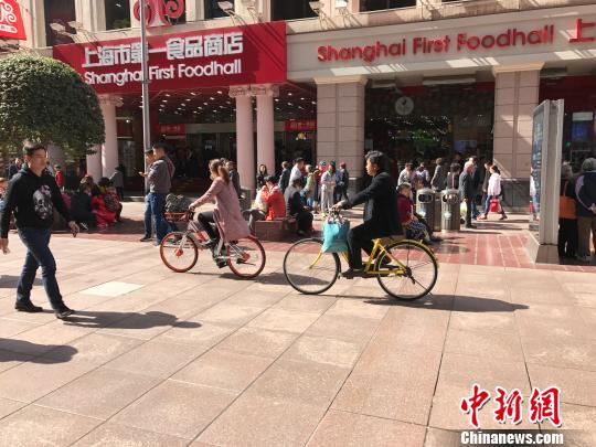 两名骑行者将共享单车骑上了上海南京路步行街。 王子涛 摄