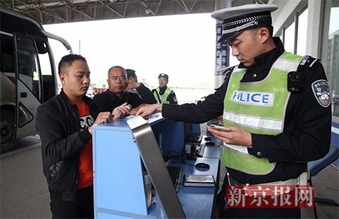 民警对进京大巴车上乘客们的身份证进行检查核实。新京报记者 尹亚飞 摄