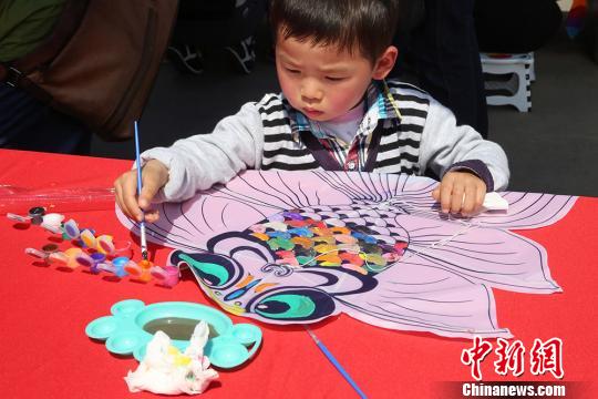 小朋友在风筝上绘制图案。 黄志毅 摄