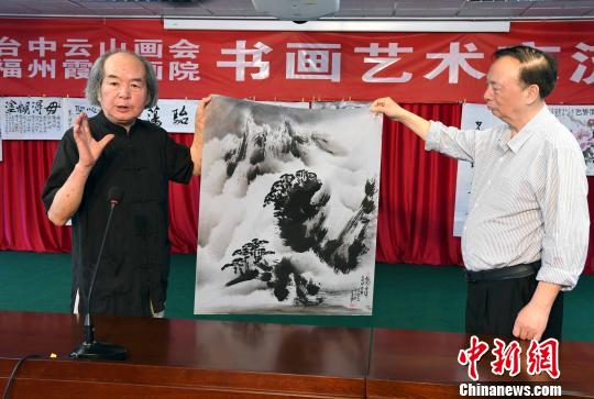 跨海前来参加书画艺术笔会交流活动的台中云山画会艺术总监、台湾著名水墨大师葛宪能(左)为福州市霞光画院院长张天金(右)介绍其现场创作画作的艺术构思。 记者刘可耕 摄