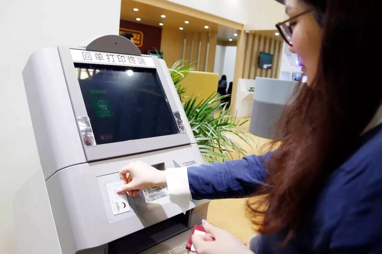 ▲ 银行工作人员演示操作自助回单打印机，凭卡号和身份证，无需排队等候
