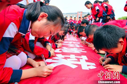21日,江西省九江县国土资源局携手该县第一小学举办“世界地球日”进校园系列活动。图为学生在“节约资源、爱护环境、保护地球”活动上签名。 黄光荣 摄
