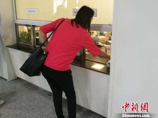 图为患者在窗口送检验液体。　张枭 摄