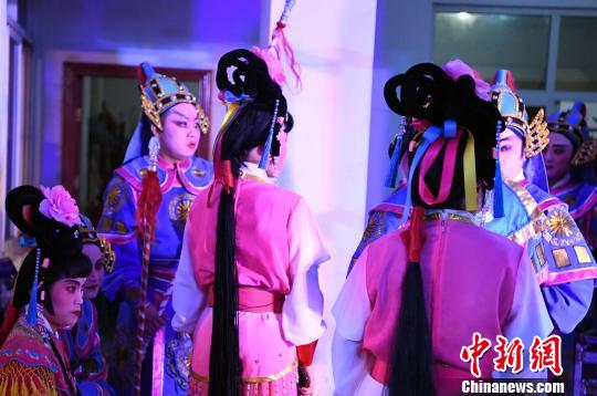 4月22日晚,化完妆的莆仙戏演员在剧场后台准备登台演出。 张斌 摄
