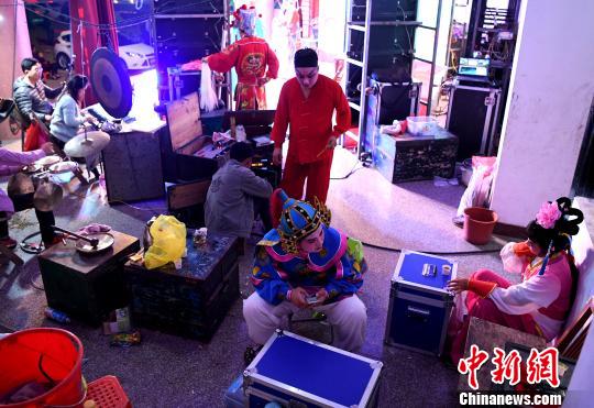 4月22日晚,化完妆的莆仙戏演员在剧场后台准备登台演出。 张斌 摄
