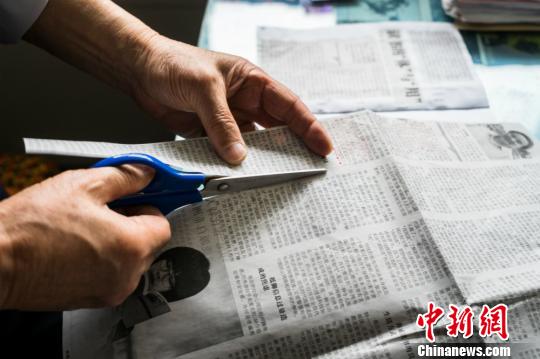 图为谈汗人在剪下自己喜欢的内容。 贾军松 摄