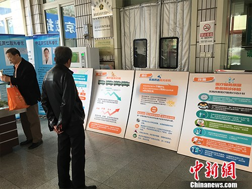 资料图:北京普仁医院外,有人在细读医改宣传板。汤琪 摄