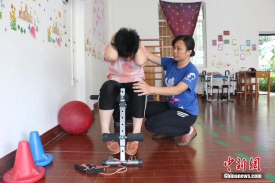 陈敬玉在帮助一名患儿做仰卧起坐训练。林馨 摄
