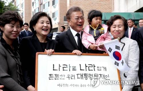 5月10日上午，文在寅（左三）和金正淑（左二）接过邻居联名庆祝入主青瓦台的匾额后喜笑颜开。来源：韩联社