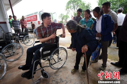 工作人员向残疾人及其家属讲解多功能轮椅的使用方法。 周亮 摄